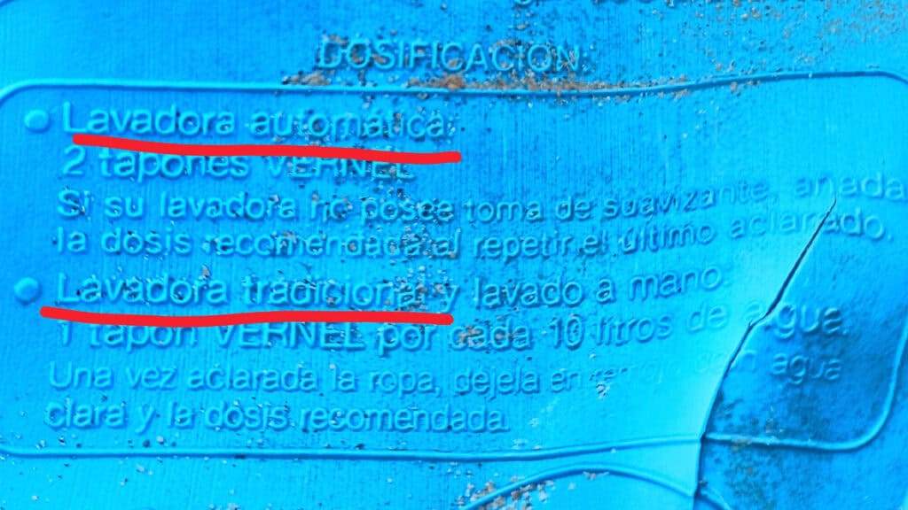 Primer plano de una etiqueta azul de instrucciones de dosificación de detergente para ropa, en la que se enumeran las directrices-borrador automático y lavadoras tradicionales-en español.