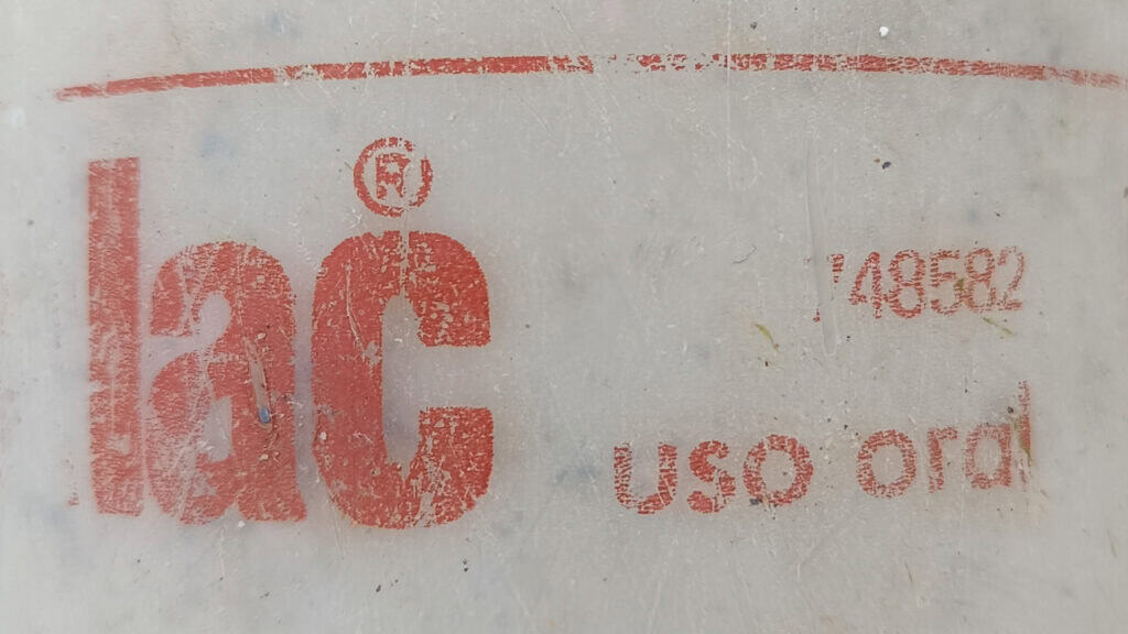 Primer plano de un texto rojo desgastado en el que se lee «lac® uso ord.» y el número «149582», impreso sobre una superficie blanca y ligeramente sucia, que se asemeja a la etiqueta de un Borrador automático.